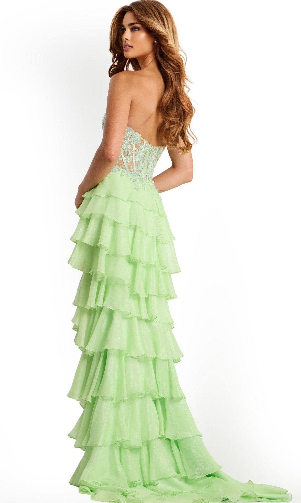 A woman models the Jovani 47422 long prom dress—a strapless, light green gown with a lace-embroidered corset bodice, tiered chiffon ruffle skirt, and sheer back—posing against a plain white background.
